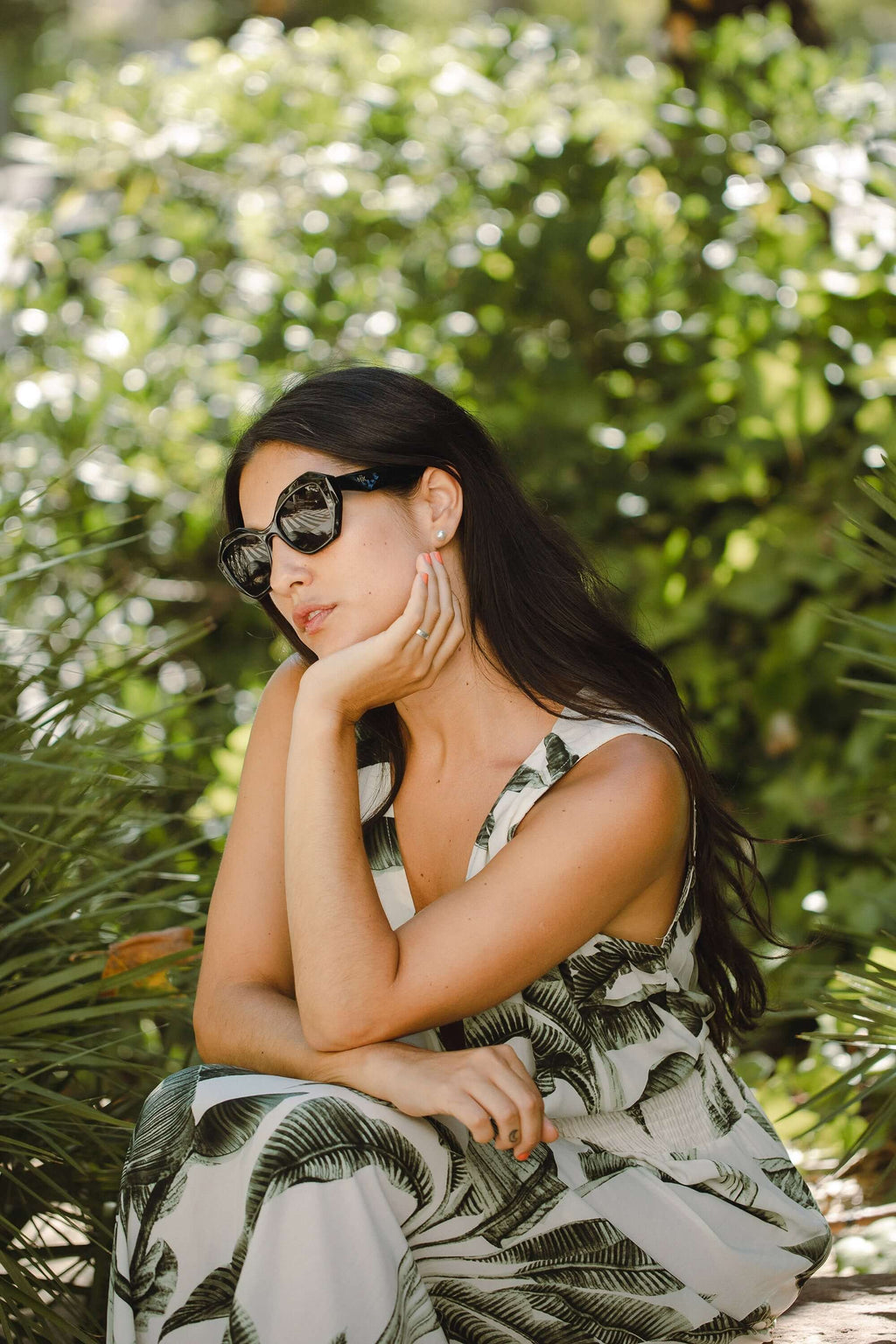Mujer usando gafas de sol Hanukeii® Moorea Black / Black en un entorno natural con plantas.