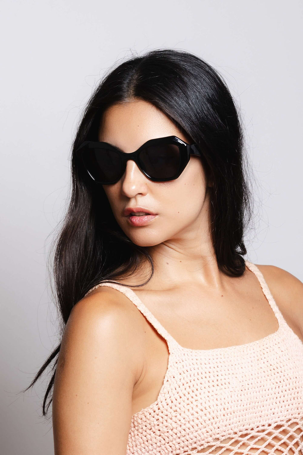 Mujer usando gafas de sol Hanukeii® Moorea Black / Black con fondo neutro.